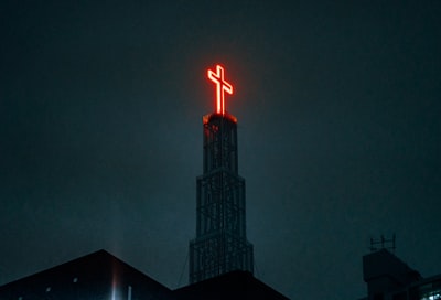 The cross of a light on the top of the building at night
